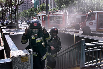 Dos bomberos salen del aparcamiento del paseo de Gràcia de Barcelona tras participar en la extinción del incendio que se declaró ayer.