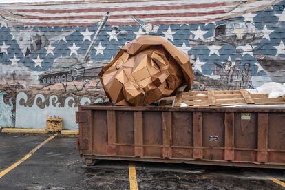 La estatua geométrica de la cabeza de Trump de casi dos metros de plástico dorado, en un contenedor de basura. |