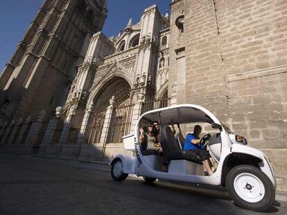 Un coche eléctrico pasa delante de la catedral de Toledo. Tiene capacidad para llevar a cuatro personas, y alquilarlo durante dos horas cuesta 40 euros.