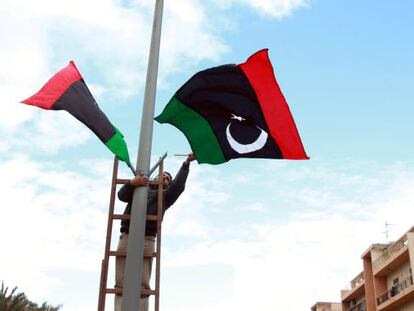 Un trabajador libio coloca banderas en Trípoli, en celebración para marcar el primer aniversario del inicio de la revuelta.