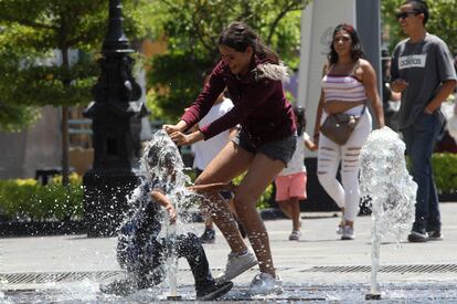 Estas anomalías térmicas, que pueden alargarse entre cuatro y diez días, son aún más intensas en las ciudades por el efecto isla de calor, un fenómeno causado por los materiales y las estructuras urbanas que atrapan el calor durante el día y lo expulsan durante la noche. En la imagen, un niño y una mujer juegan dentro de una fuente en Guadalajara.