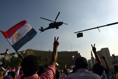Un manifestante egipcio hace el signo de victoria mientras un helicóptero sobrevuela la plaza Tahrir de El Cairo (Egipto), 4 de julio de 2013.