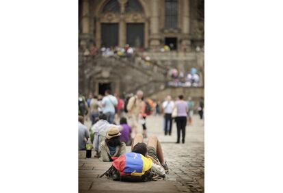 Un peregrino descansa apoyado en su mochila ante la catedral de Santiago de Compostela.