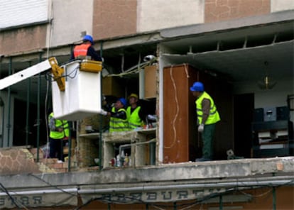 Varios operarios trabajan en la fachada derruida por la explosión.
