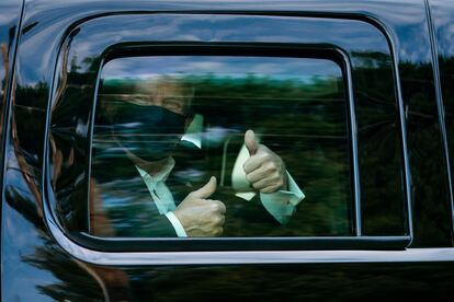 El presidente Donald Trump saluda desde el coche tras salir del hospital militar.