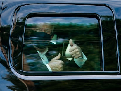 El presidente Donald Trump saluda desde el coche tras salir del hospital militar.