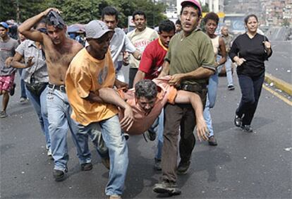 Seguidores del presidente venezolano Hugo Chávez ayudan a un herido de bala durante los enfrentamientos entre dichos seguidores y la policía de Caracas.