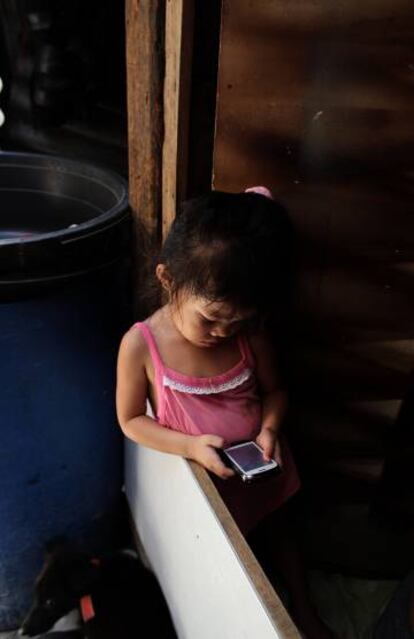 Una niña de tres años juega con el 'smartphone' de su padre en Manila, Filipinas.