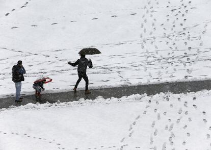 Varias personas acceden a un centro escolar de la localidad de Uharte por un camino abierto entre la nieve acumulada tras la intensa nevada que ha caído durante esta noche en buena parte de Navarra.