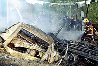 Los bomberos intentan sofocar el fuego entre el amasijo de coches después del accidente.