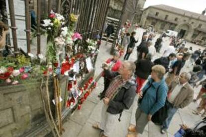 Numerosos peregrinos, visitantes y vecinos de la ciudad dejan bastones, notas, velas y flores delante de la puerta principal de la catedral de Santiago.