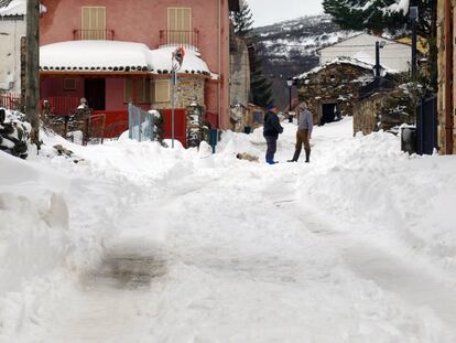 Dos vecinos de La Acebeda conversan en una calle nevada.