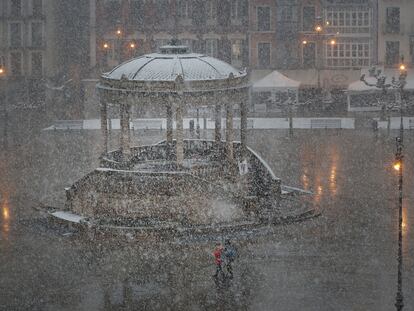 Dos personas cruzan la Plaza del Castillo de Pamplona bajo una intensa nevada, este viernes.