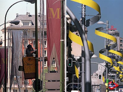 Un operario coloca banderolas en las farolas del centro de Madrid. A la derecha, adornos desplegados en la Gran Vía, por donde pasarán los novios.