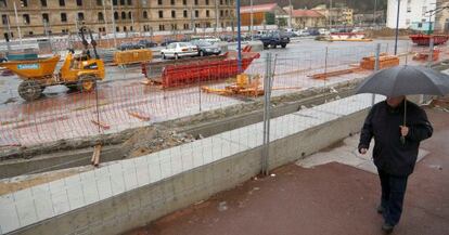 Una persona pasa al lado de las obras de construcción de la nueva estación de autobuses de Atotxa, en el centro de San Sebastián