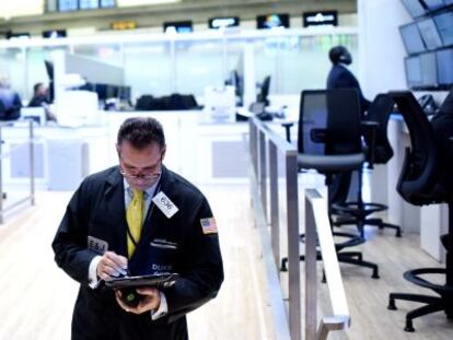 Un corredor burs&aacute;til observa una tableta, en el recinto de la Bolsa de Wall Street (Nueva York). 