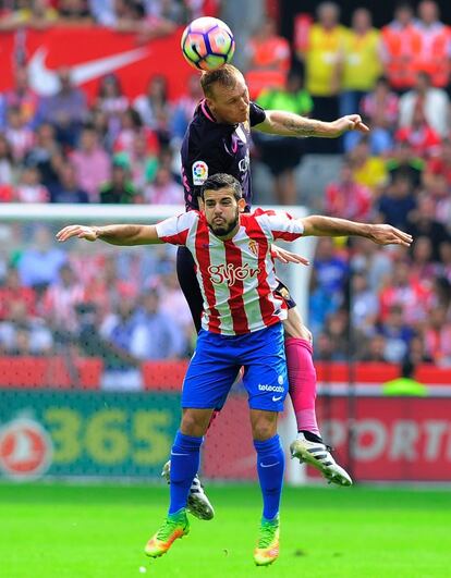 El defensa francés del FC Barcelona, Jeremy Mathieu (arriba), golpea el balón junto con Víctor del Sporting.

