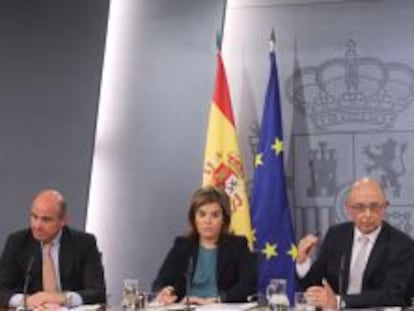 La vicepresidenta del Gobierno, Soraya Sáenz de Santamaría, acompañada del ministro de Economía, Luis de Guindos, y el de Hacienda, Cristóbal Montoro, en la rueda de prensa posterior al consejo de ministros que ha aprobado los Presupuestos Generales del Estado 2015.