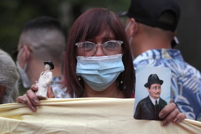 Una mujer sostiene una figura y una fotografía del médico venezolano José Gregorio Hernández.