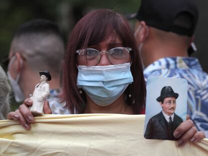 Una mujer sostiene una figura y una fotografía del médico venezolano José Gregorio Hernández.