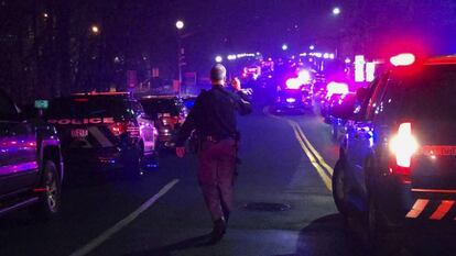 Un agente de la policía en la calle rodeado de coches de patrulla. 