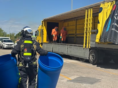 Unos bomberos, algunos de ellos de la unidad NRBQ, con monos naranja retiran las garrafas del escape en la nave de Algete.