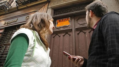 Una pareja de j&oacute;venes en el portal de un piso en alquiler. 