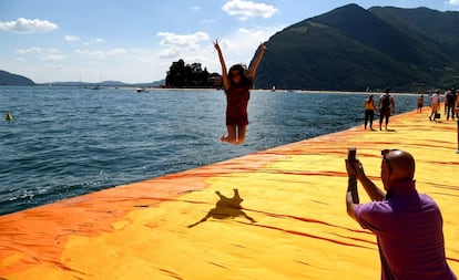 Una visitante de 'Los muelles flotantes', de Christo y Jeanne-Claude, salta sobre la pasarela efímera.