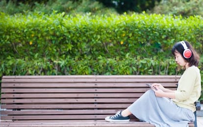 Una mujer escuchando música en una tableta en un parque de Taiwán.