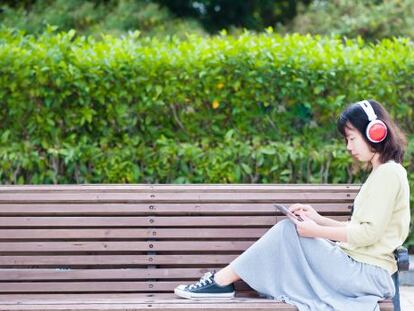 Una mujer escuchando música en una tableta en un parque de Taiwán.