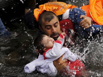 Un refugiado sirio sujeto a su hijo a su llegada a Lesbos.