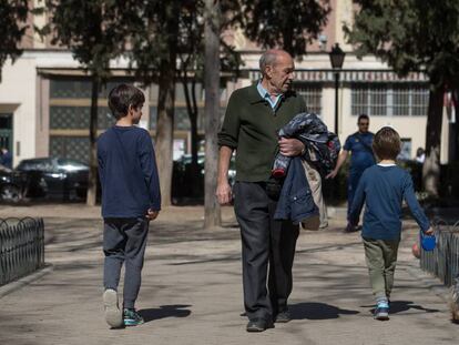 Dos niños y un hombre mayor pasean por un parque de Madrid.
