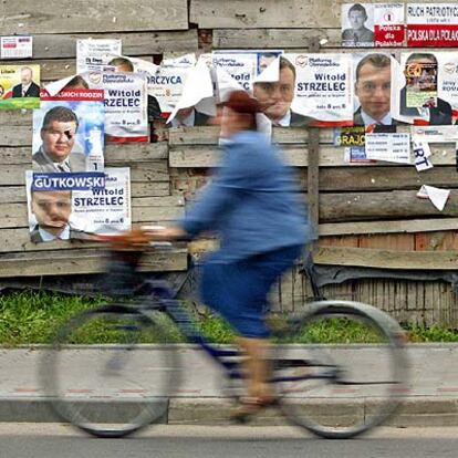 Una ciclista pasa delante de una pared con carteles electorales en Paslek.