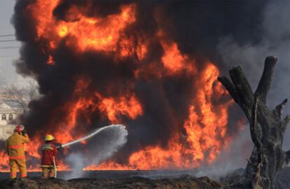 Los bomberos intentan apagar las llamas tras provocadas tras la explosión del oleoducto.