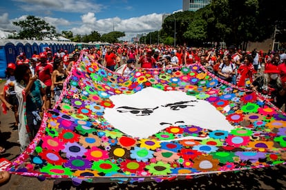 Personas despliegan una manta con la cara de Lula entre flores, este domingo en Brasilia.
