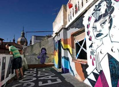 La terraza del quinto piso del Patio Maravillas, con los tejados de Malasaña de fondo, sirve de escenario para las obras temporales del taller de arte urbano.
Arriba, las escaleras decoradas con los restos de una exposición. A la derecha, la entrada.