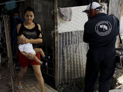 Una mujer cubre la boca de su beb&eacute; mientras un operario fumigaba ayer su chabola en el suburbio de El Capio, en San Jos&eacute; de Costa Rica. 