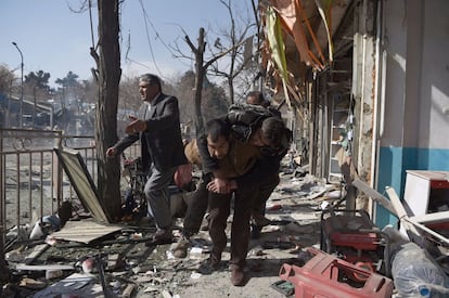 El número de muertos por el atentado suicida talibán en el centro de la capital afgana roza ya el centenar, mientras que los heridos se sitúan en 158, según el Gobierno. En la imagen, un hombre traslada un herido tras la explosión, el 27 de enero de 2018.