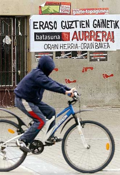 Un joven ciclista pasa delante de unos carteles de Batasuna, en Pamplona.