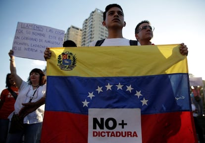 Un partidario de la oposición tiene una bandera venezolana con una señal que dice "No más dictadura" durante una protesta contra el gobierno del presidente venezolano Nicolás Maduro, en Caracas, Venezuela.