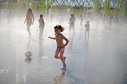 Varios niños juegan en los surtidores de agua de los jardines de la Arganzuela en Madrid, junto al recuperado río Manzanares.