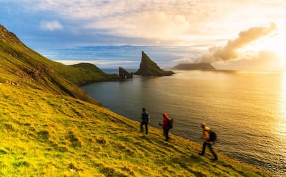 Excursionistas rumbo a Drangarnir, dos peñones de roca junto a la isla de Vágar, en las Feroe.