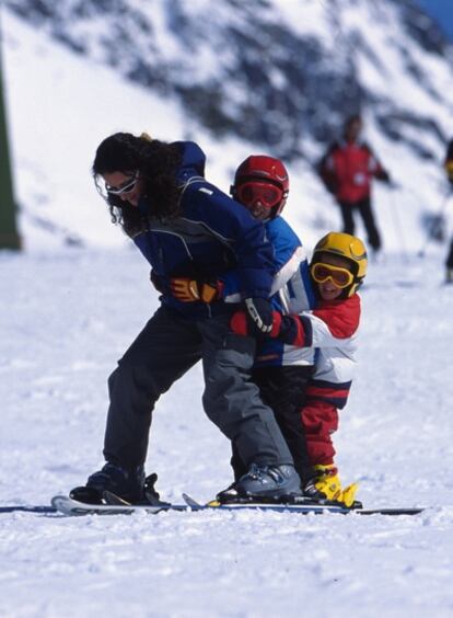 Una mujer juega con dos niños en una pista de la estación de Baqueira Beret.