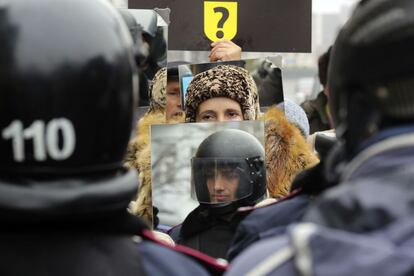 Una manifestante pro europea porta un espejo en el que ve el reflejo de un policía perteneciente a la línea de policial bloqueando la sede del gobierno en Kiev.