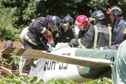 Un grupo de bomberos trabaja para rescatar del interior de la avioneta el cuerpo de uno de los fallecidos.