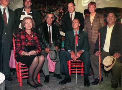 Los reyes Juan Carlos y Sofía sentados en sillas de enea en el interior de una chabola del poblado de La Celsa, Madrid. Junto a ellos, el Tío Isidoro y su hijo.