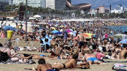 Turistas y vecinos en la playa de la Barceloneta, en Barcelona.  