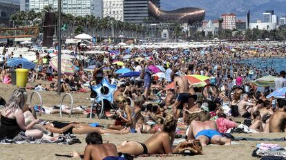 Turistas y vecinos en la playa de la Barceloneta, en Barcelona.