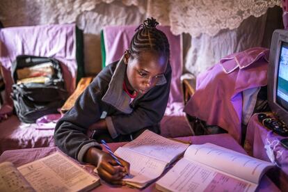 Sheila Achieng, una joven estudiante del asentamiento informal de Kibera, en Kenia, haciendo los deberes.