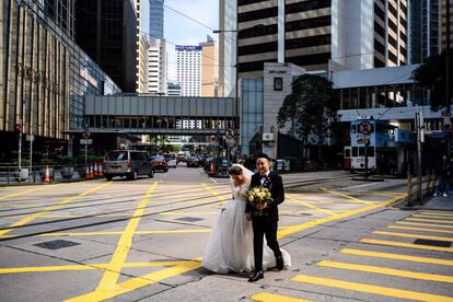 Una pareja cruza una calle en el distrito Central de Hong Kong durante una sesión de fotos nupciales.